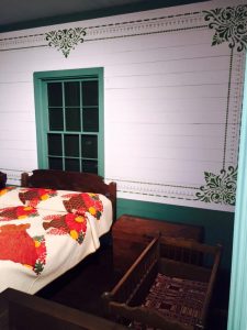 Stenciled wall and child's cradle in Texas Room